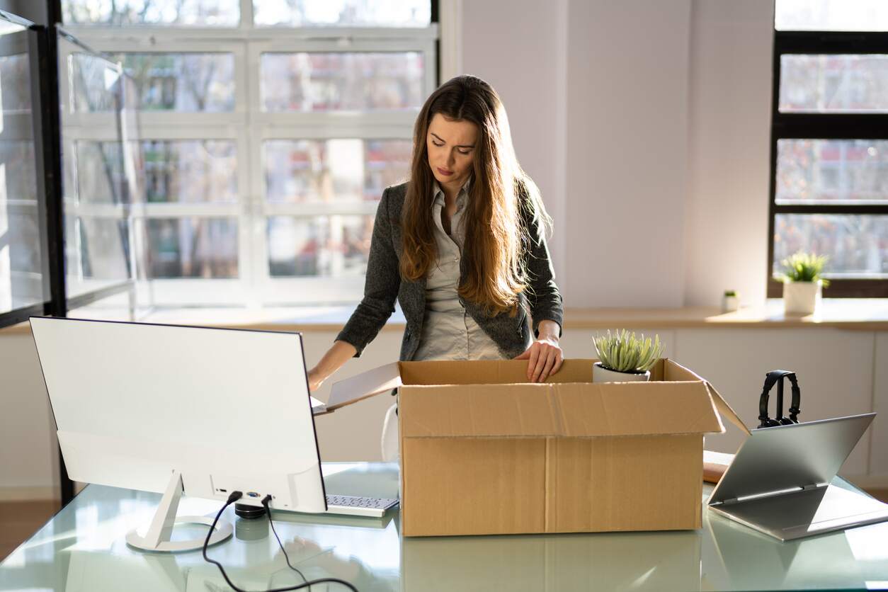 Woman packs box as she moves out of office